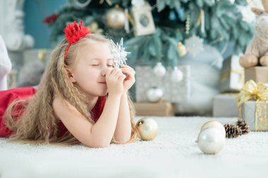 5 yaşında bir kız. Noel ağacının yanında şeker kamışı şekerlemesi var..