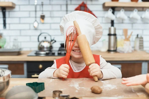 Vaření je zábava. Malá kuchařka si hraje s moukou. Mladá dívka pracuje na těstě s válečkem, aby perník sušenky. — Stock fotografie