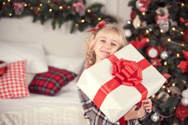 Mutlu heyecanlı kız çocuğu Noel hediyesi kutusunu tutuyor..