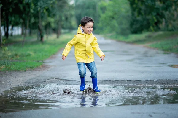 ぬれた子供が水たまりに飛び込んでいる。路上で楽しい。夏の気温 — ストック写真