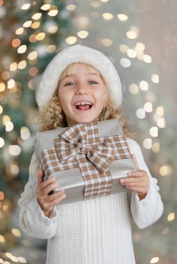 Mutlu heyecanlı kız çocuğu Noel hediyesi kutusunu tutuyor..