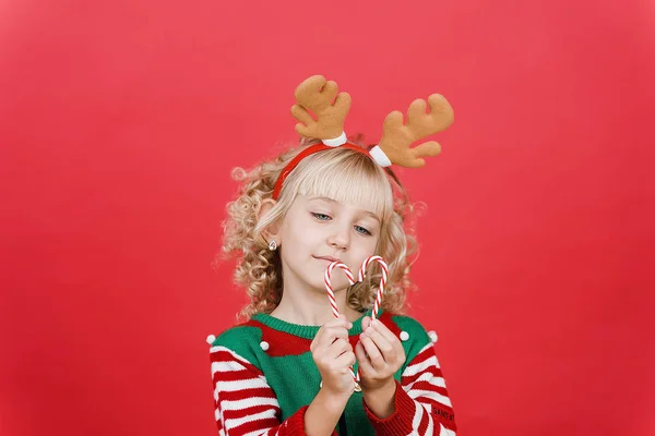 Niña en traje de ayudante de Santa elfo sobre fondo de color vivo rojo brillante . — Foto de Stock