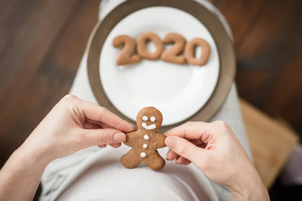 Gewassen foto van zwangere vrouw met nummer 2020 van gember koekjes op buik. — Stockfoto