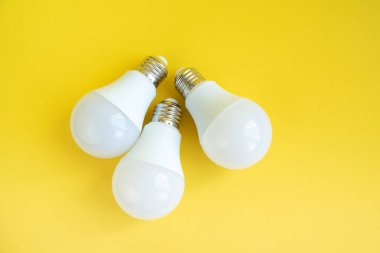Sarı arka planda üç tane öncü ampul, enerji tasarrufu kavramı