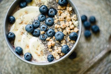 Sağlıklı kahvaltı berry smoothie kase muz ve yaban mersini ve chia tohumu ile granola ile tepesinde . vegan çiğ gıda konsepti 