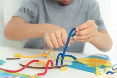 Dantel, ip ve makarna ile oynayan çocuk ellerini kapat. Kaliteli motor becerilerin gelişimi. Erken eğitim, Montessori Metodu. Bilişsel beceriler,