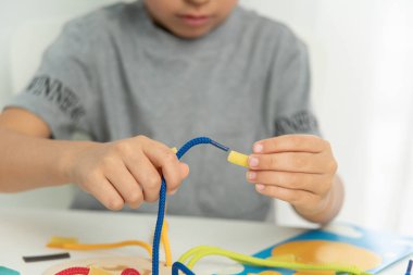 Dantel, ip ve makarna ile oynayan çocuk ellerini kapat. Kaliteli motor becerilerin gelişimi. Erken eğitim, Montessori Metodu. Bilişsel beceriler,