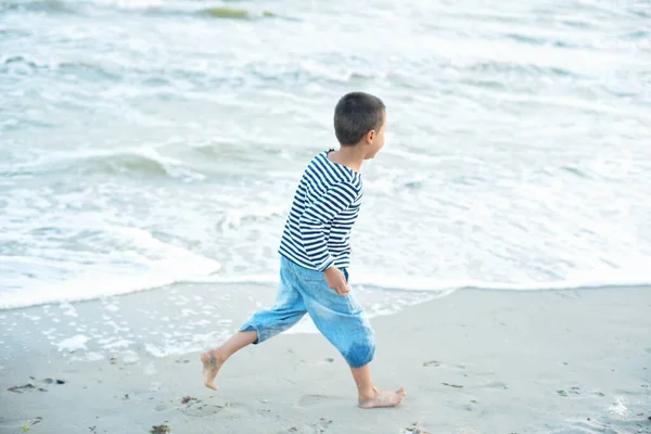 青い海の水しぶきの近くの海岸で走っている小さな子供 — ストック写真