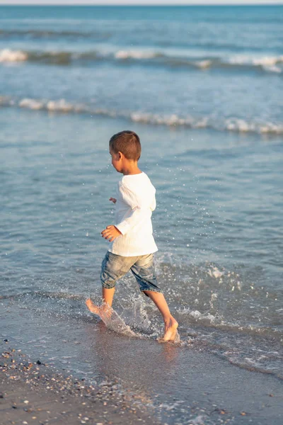 青い海にビーチの海岸の水しぶきを実行している小さな子供 — ストック写真