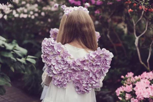 带着紫色蝴蝶翅膀和花冠的小女孩站在公园里盛开的杜鹃中间的倒影 童年和假日的概念 — 图库照片