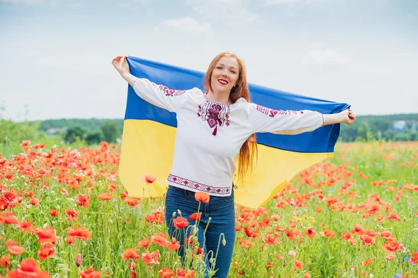 Dziewczyna niesie trzepotanie niebiesko-żółta flaga Ukrainy na polu. — Zdjęcie stockowe