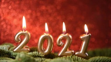Tatil geçmişi. Mutlu yıllar 2021. 2021 yılının rakamları. Kırmızı şenlikli ışıl ışıl arka planda yanan altın mumlar..