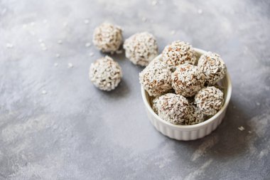 Sağlıklı ev yapımı çiğ paleo çikolata enerji topları, kakao ve susamlı hindistan cevizi ve gri arka planda chia tohumları..