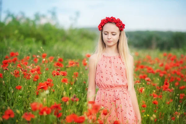ウクライナ語美しいです女の子で花花輪歩行の間にケシで夏フィールドで晴れた日 — ストック写真