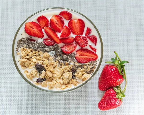 Healthy breakfast superfood smoothie bowl topped with granola and strawberry. close up.