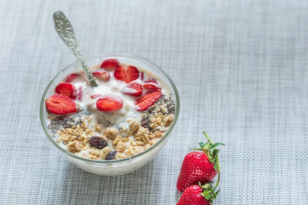 Healthy breakfast superfood smoothie bowl topped with granola and strawberry. close up.