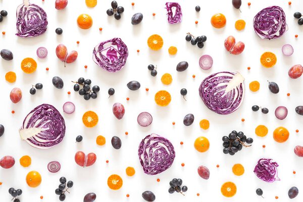 Composition of vegetables and fruits on a white background. Pattern made from fresh vegetables and fruits. Top view, flat design. Collage of red cabbage in a cut, plums, grapes, mandarins