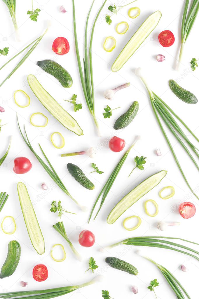 Abstract composition of vegetables. Vegetable pattern. Food background.Top view. Large and small cucumbers, garlic, tomatoes and green onions on a white background. Vertical orientation of the frame