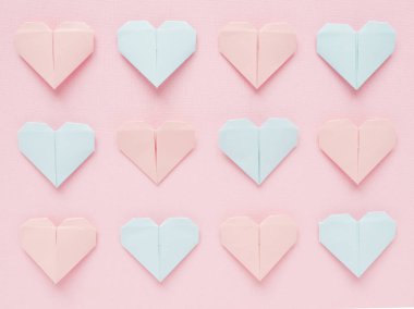 Pembe bir arka plan üzerinde kağıt origami kalplerin desen