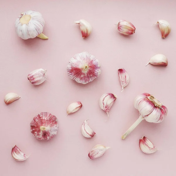Food composition with garlic and cloves on pink background