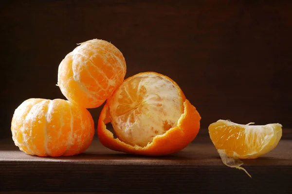 Half-peeled mandarines and peel on wooden surface, minimalistic still life