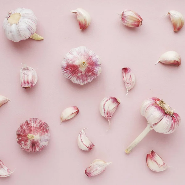 Food composition with garlic and cloves on pink background