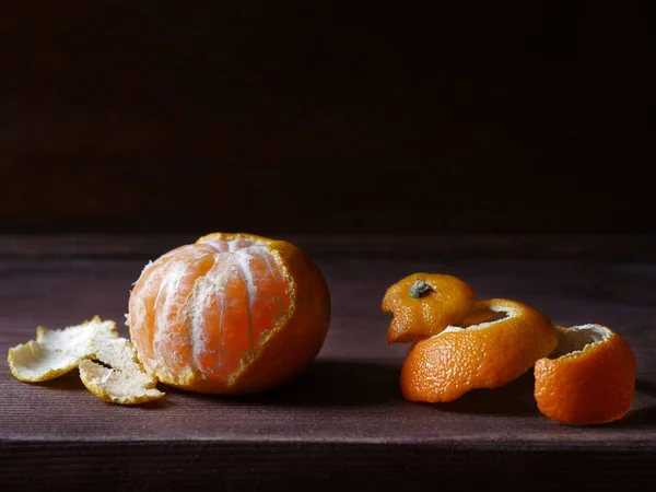 Half-peeled mandarin and peel on wooden surface, minimalistic still life