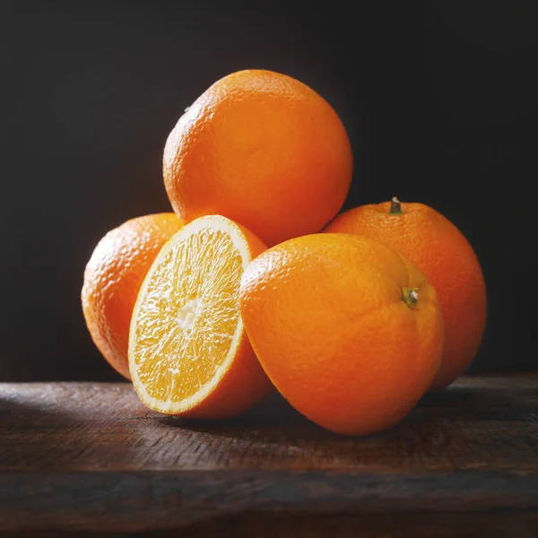 Крупный План Апельсинов Тремя Целыми Деревянном Столе Черном Фоне — стоковое фото