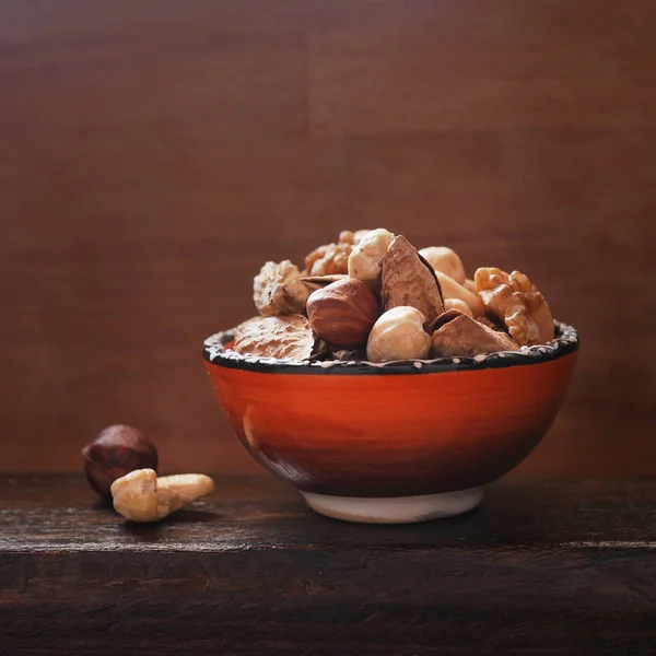 Different Nuts Orange Ceramic Cup Wooden Board — Stock Photo, Image