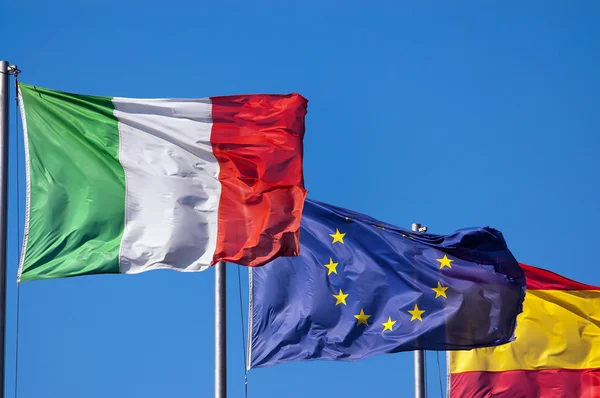 Italienische und spanische Flaggen am blauen Himmel — Stockfoto