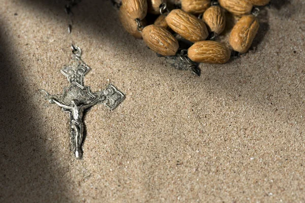 Crucifix en argent avec perles de chapelet sur sable — Photo