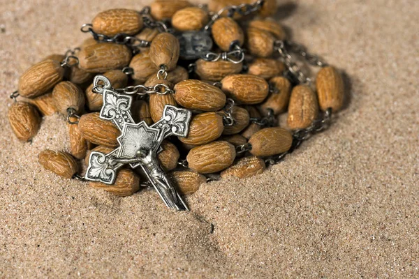 Crucifixo de prata com grânulos de rosário na areia — Fotografia de Stock