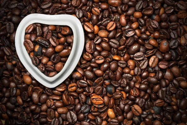 Granos de café en un tazón en forma de corazón — Foto de Stock