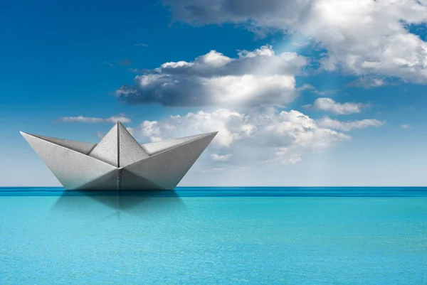 Papírový člun v tyrkysovém moři s modrou oblohou a mraky — Stock fotografie