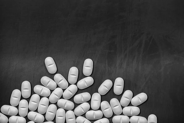 Witte pillen verspreid over een schoolbord met kopieerruimte — Stockfoto