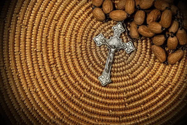 Vieux crucifix argenté et chapelet en bois sur texture en osier tissé — Photo