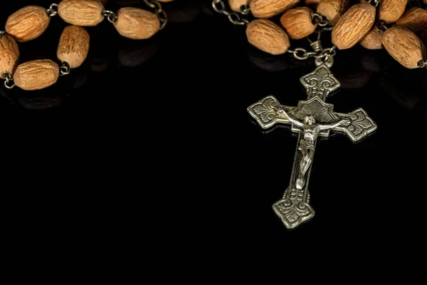 Old silver crucifix with wooden rosary bead on black background — ストック写真