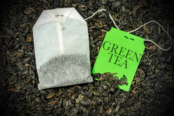 Nahaufnahme eines grünen Teebeutels auf vielen trockenen Blättern - Schwarzpulvertee — Stockfoto