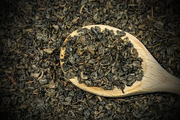 Hojas secas de té verde de pólvora sobre una cuchara de madera Imágenes de stock libres de derechos