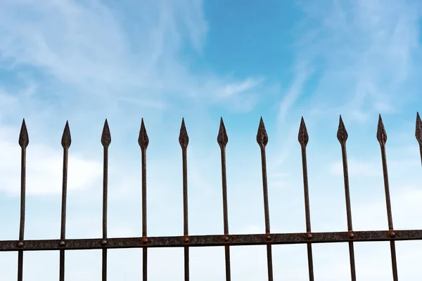 Recinzione in ferro battuto con punti taglienti sul cielo blu con nuvole — Foto Stock
