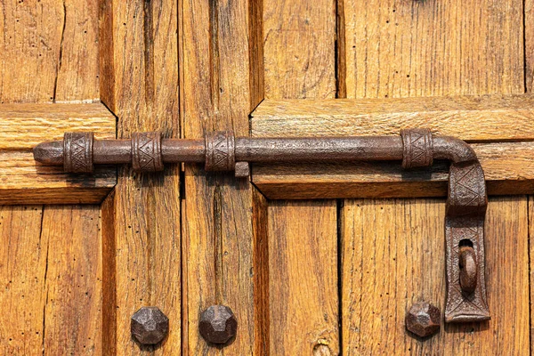 Puerta de madera vieja con pestillo de hierro forjado y pernos —  Fotos de Stock