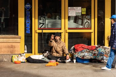 BOLOGNA, EMILIA-ROMAGNA, ITALY, - FEB 23, 2020: A homeless person with his dog asks for alms in front of a bank in Via Rizzoli, in Bologna downtown on a winter Sunday. Emilia-Romagna, Italy, Europe