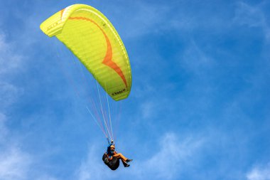 SCHWANGAU, ALMANY - 9 SEP 2018: Sarı ve turuncu paraglider, arka planda bulutlarla mavi gökyüzünde uçuyor. Schwangau, Bavyera, Almanya