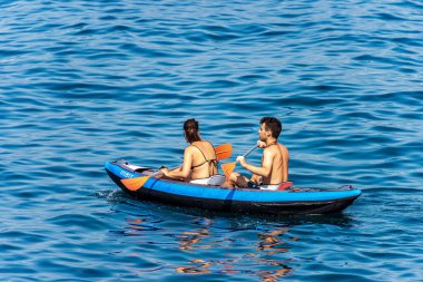 Los Angeles SPEZIA, LIGURIA, İTALYA - 21 Temmuz 2019: Genç bir çift, şişme bir kanoyla mavi denizde kürek çekiyor. La Spezia Körfezi, Liguria, İtalya, Avrupa
