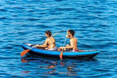 Los Angeles SPEZIA, LIGURIA, İTALYA - 21 Temmuz 2019: Genç bir çift, şişme bir kanoyla mavi denizde kürek çekiyor. La Spezia Körfezi, Liguria, İtalya, Avrupa
