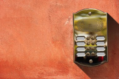 Fotokopi alanı, İtalya ve Avrupa olan kırmızı bir duvarda sekiz kapı zili olan pirinç bir dahili telefonun yakın çekimi.