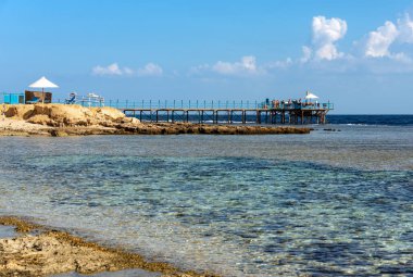 Dalış, şnorkelle yüzme ve deniz manzarası için kullanılan mercan resifinin üzerindeki ahşap iskele. Marsa Alam yakınlarında Kızıldeniz, Mısır, Afrika.