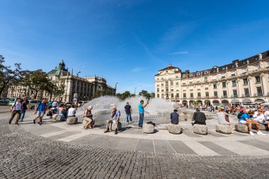 MÜZİK, GERMANY - SEPT 6, 2018: Karlsplatz veya Stachus 'taki bir grup insan, Münih' in ortasında çeşmeli büyük bir meydan, arka planda Adalet Sarayı (Justizpalast).