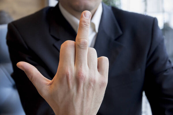 Человек в деловом костюме показывает средний палец ебать
