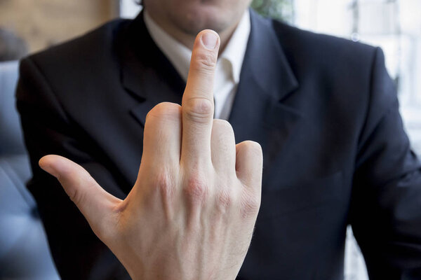 Человек в деловом костюме показывает средний палец всем
